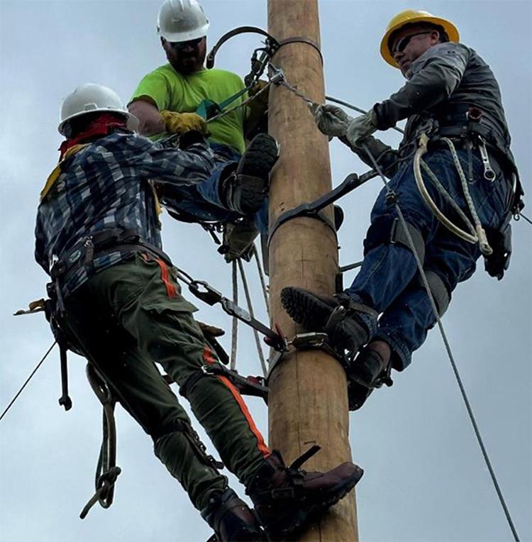 Steele-Waseca’s Gabe Roetman (middle) collaborated with fellow team members in Jamaica hanging wire after new poles were set.